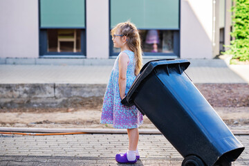 Little preschool girl with glasses taking garbage can. child learning waste sorting. Environment...