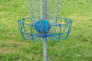 Blue disc resting in basket. Standard disc golf basket, close-up. Outdoor activity