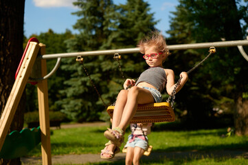 Obraz premium Girl swinging outdoors on playground swing