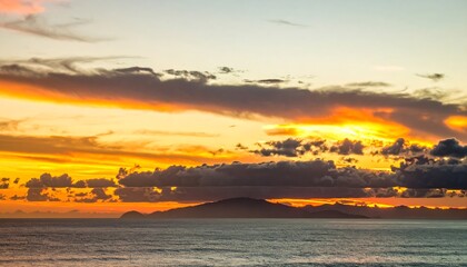 Dramatic sunset over the ocean with colorful clouds and distant island