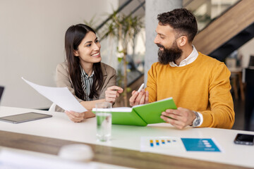 Obraz premium Smiling Business Professionals Collaborating Over Documents in a Stylish Office Setting
