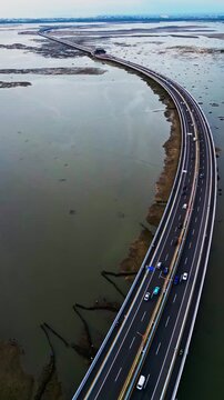 Aerial footage shows Bali Mandara Toll road built as a bridge over exposed mudflats during low tide the tropical highway scene reveals modern engineering cutting across coastal tidal landscape