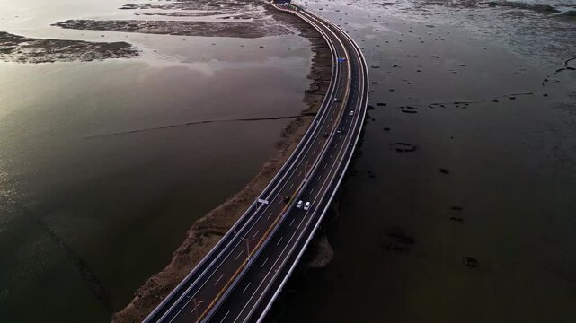 From above Bali Mandara Toll road curves across wide tidal mudflats revealed at low tide the drone footage highlights tropical coastal patterns and the strong design of the island bridge