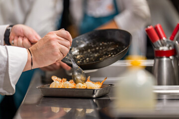 Gros plan sur un chef étoilé en pleine préparation et cuisson d’un plat gastronomique dans sa cuisine professionnelle.