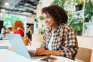 A Young Woman Engaged in Work on Her Laptop in a Contemporary and Stylish Cafe Setting