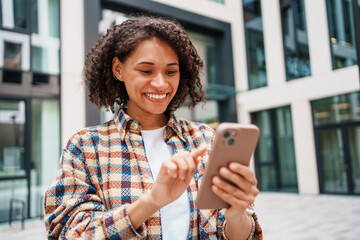 A young woman casually engaged with her smartphone while enjoying a vibrant urban setting