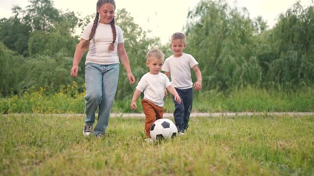 Boy girl smile as each child joins game. Kid is playing football on green grass. Soccer fun grows when ball rolls fast. Game time is joy every boy and girl share moments. Child runs ball on soft grass
