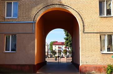 Fototapeta premium Arch in a residential brick house leading to a square in the city of Bobruisk