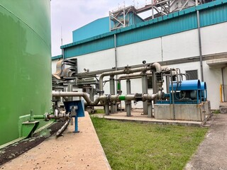 Industrial landscape featuring a green storage tank and complex piping systems, showcasing...