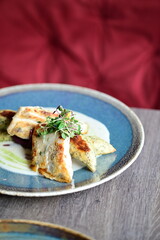 Grilled fish fillet with white sauce and herbs on a plate