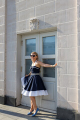 A girl with blond hair dressed in vintage nautical style dresses on the embankment of the river...