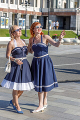 Two girls dressed in vintage nautical style dresses on the embankment of the river station, port.