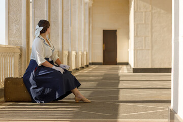 A girl stands with a suitcase in her hands on the embankment of the river station, port.