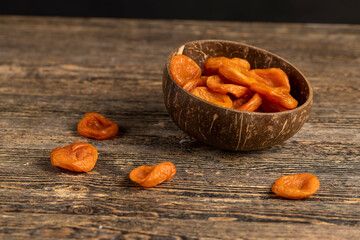 orange dried apricots made from ripe apricots in a coconut shell plate, dried apricots in a bowl made from natural materials