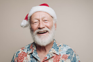 happy bearded elderly man in a floral Hawaii shirt and Santa hat, neutral studio background