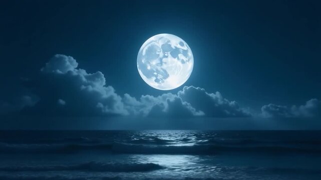 A full moon rises above the ocean waves at night, creating a beautiful and peaceful scene