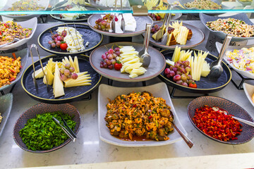 Buffet table with cheese, grapes, fresh vegetables and salads