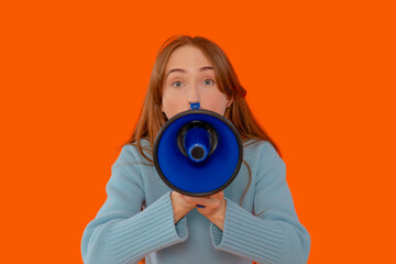 Fototapeta premium Young woman holds megaphone to convey an important message against vibrant orange backdrop during an energetic gathering in the afternoon