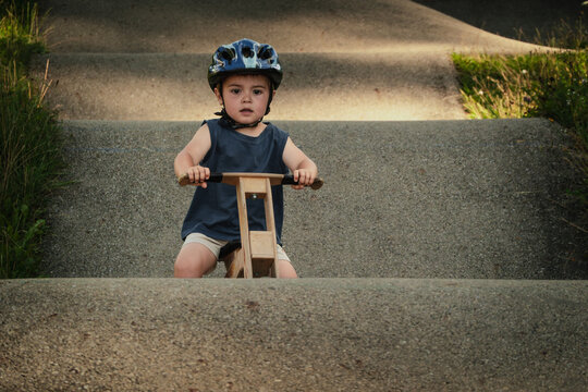 Child wearing a helmet on a balance bike overcomes obstacles on a pump track, having a great time