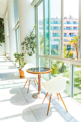 Modern interior with glass wall, table and chairs in bright sunlight