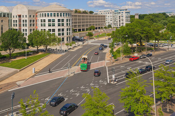 A red and green double-decker tour bus drives past downtown intersections near the East Building of the National Gallery of Art.