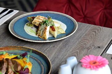 Grilled fish fillet with white sauce and herbs on a plate