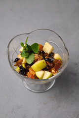 Fruit salad with mint in a decorative glass bowl.