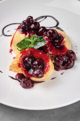 Delicious cherry pancakes with fresh mint on a white plate.