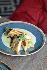 Grilled fish fillet with white sauce and herbs on a plate
