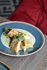 Grilled fish fillet with white sauce and herbs on a plate