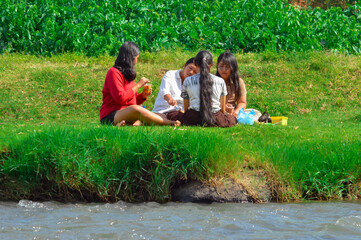 A group of four teenage girls enjoys grilling chicken and skewers on a portable stove, with one...