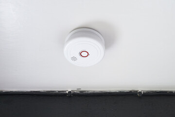 Newly installed smoke detector located on the ceiling of an old, listed farm house. Note the...