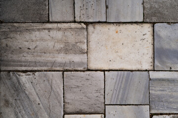 Textured marble tiles in shades of gray and white are arranged in a geometric pattern, highlighting the natural beauty and elegance of stone flooring in a contemporary architectural environment