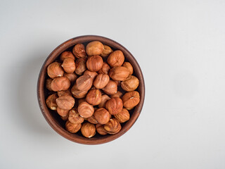 Raw hazelnuts without shells in a bowl on a white background
