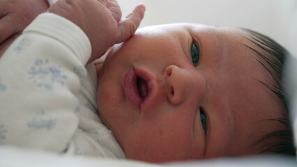 Close-up of a newborn baby grimacing and moving with curiosity, active expressions and movements...