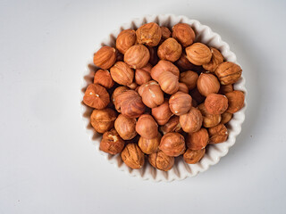 Raw hazelnuts without shells in a bowl on a white background
