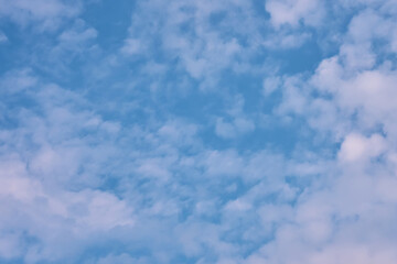 The sky is blue with clouds. The sun shines brightly, making the sky even brighter. The landscape is peaceful and serene.