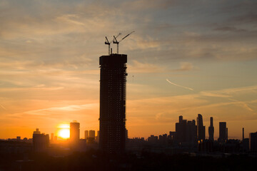 Building under construction against the backdrop of a yellow sunset