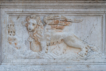 Stone carving of winged Venetian lion, historic symbol of Venice Republic on ancient well in Krk, Croatia