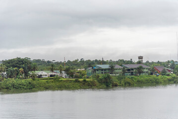 Fototapeta premium Village houses surrounded by tropical greenery along the riverbank near Buenaventura.