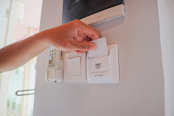 From below of crop anonymous female tourist putting card key into into switch in modern hotel room...