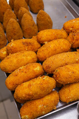 Crocchè di patate e arancini di riso nella vetrina da vendita di una pizzeria