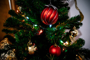 Beautiful decorated Christmas tree with red baubles and golden ribbons, creating a festive and cozy holiday atmosphere.
