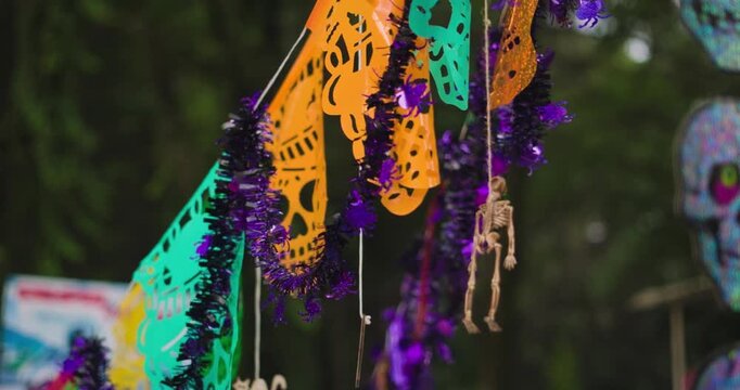 String of colourful skull Dia de los Muertos decoration hangs from gravestones