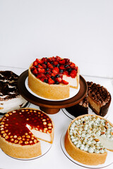 Variety of delicious cheesecakes displayed on a wooden stand with decorative toppings
