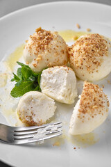 Creamy dessert with nuts and mint on a white plate