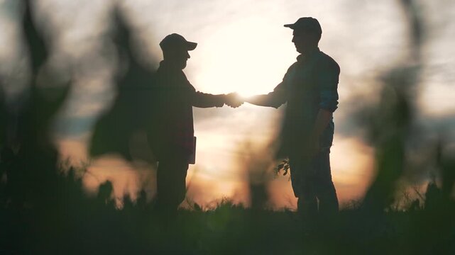 Handshake under sunset field builds partnership teamwork. Farmer man join forces agreement brings success. Nature teamwork handshake green field strengthens farmer partnership trust for long success.