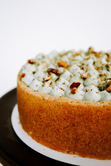 Delightful dessert featuring a soft cake topped with creamy icing and nuts on a dark plate