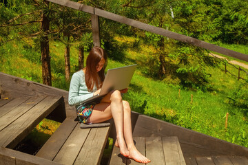 A barefoot girl enjoys online education in the forest.