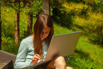 A girl studies online while enjoying the calm of nature.